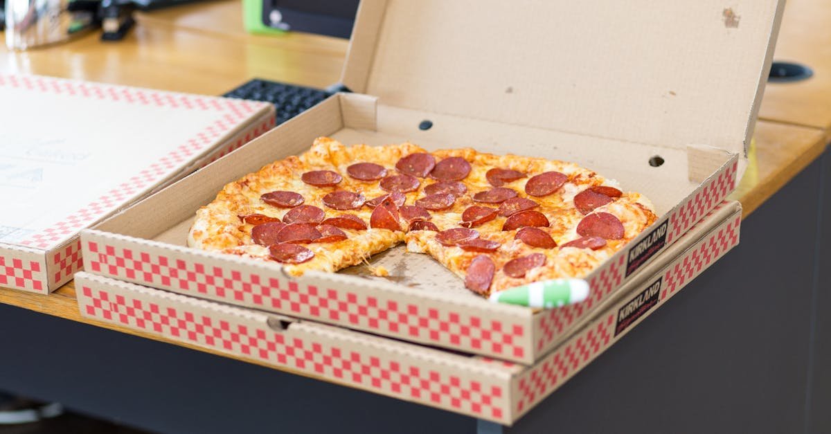 Delicious pepperoni pizza in an open box on a desk, perfect for a quick meal.