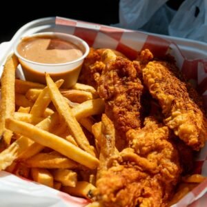Delicious crispy fried chicken with golden french fries in a takeout container, perfect comfort food.